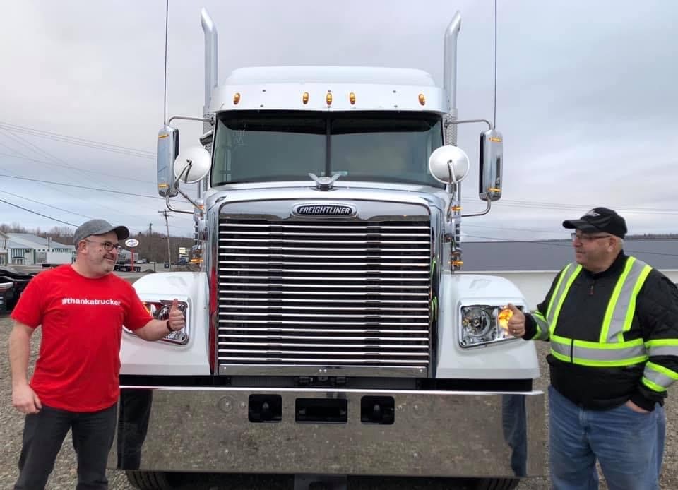 Father and son standing by the company truck
